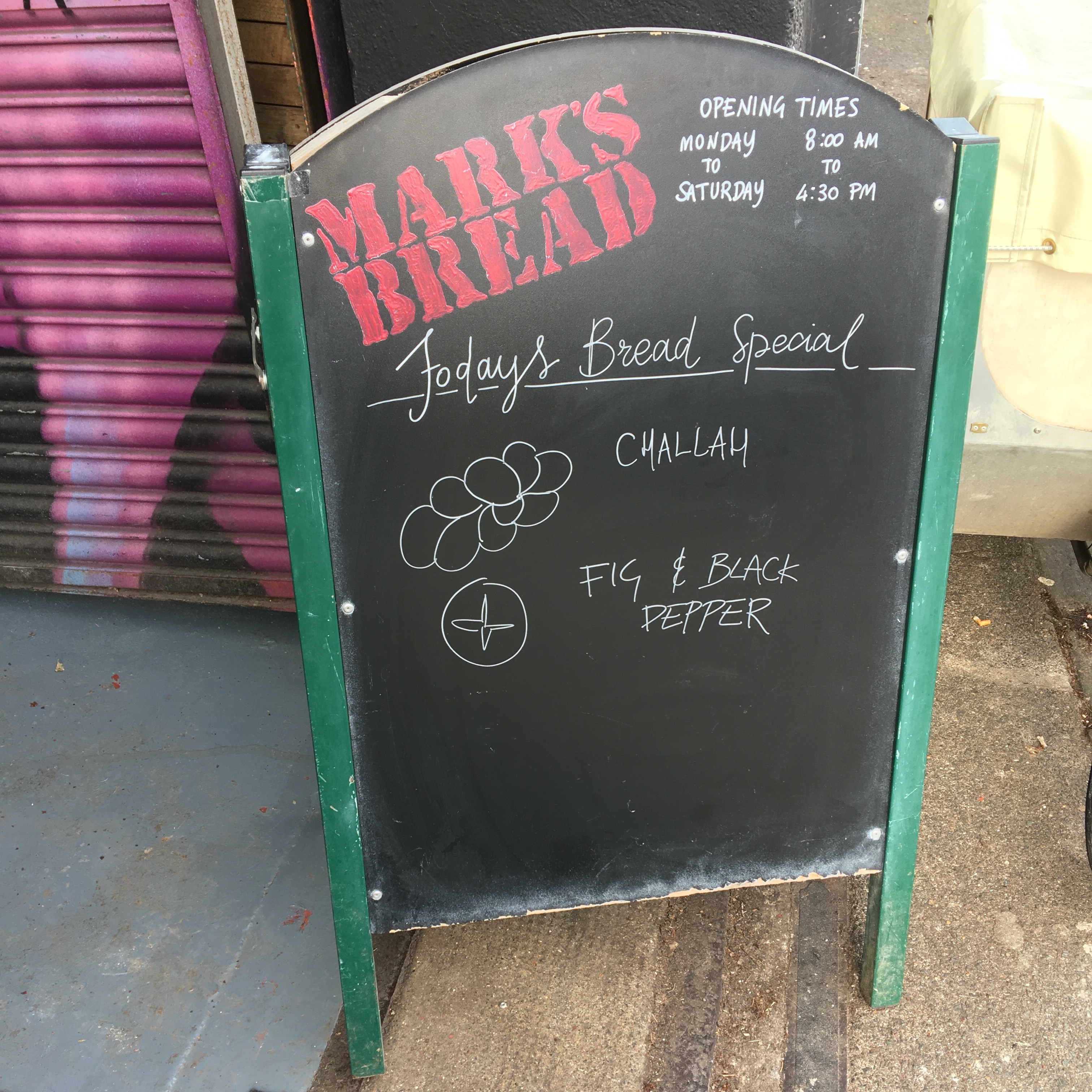 The sign outside Marks bread listing the daily specials. That day it was Challah and Fig and Black Pepper sourdough